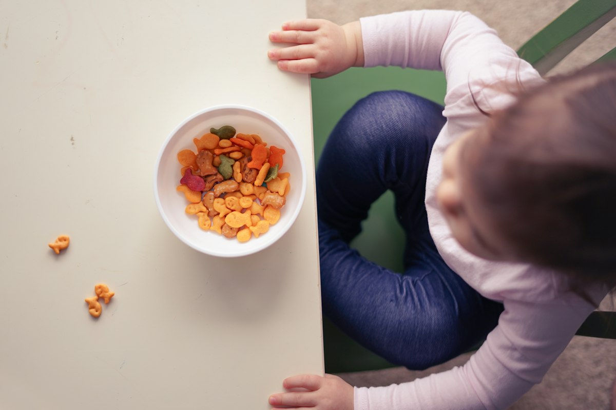 A baby in a high chair with a bowl of vegetables