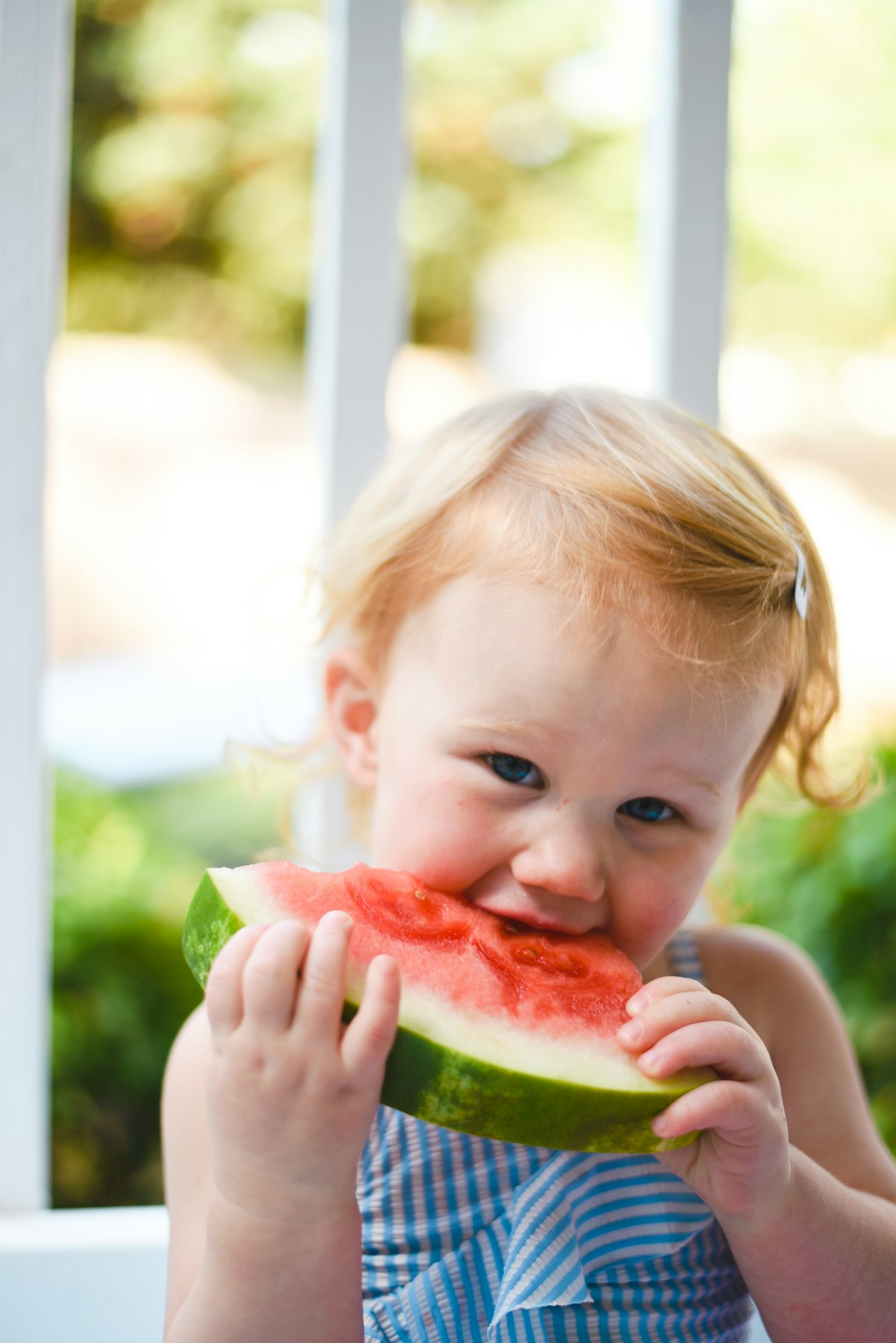 A toddler happily eating watermelon